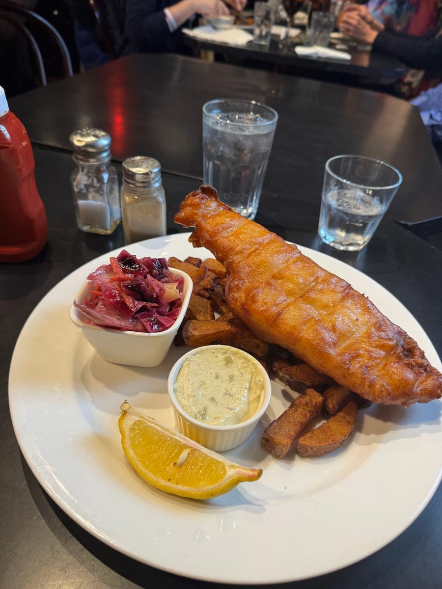 A crisp fish fillet with potatoes, red cabbage slaw, tartar sauce and lemon