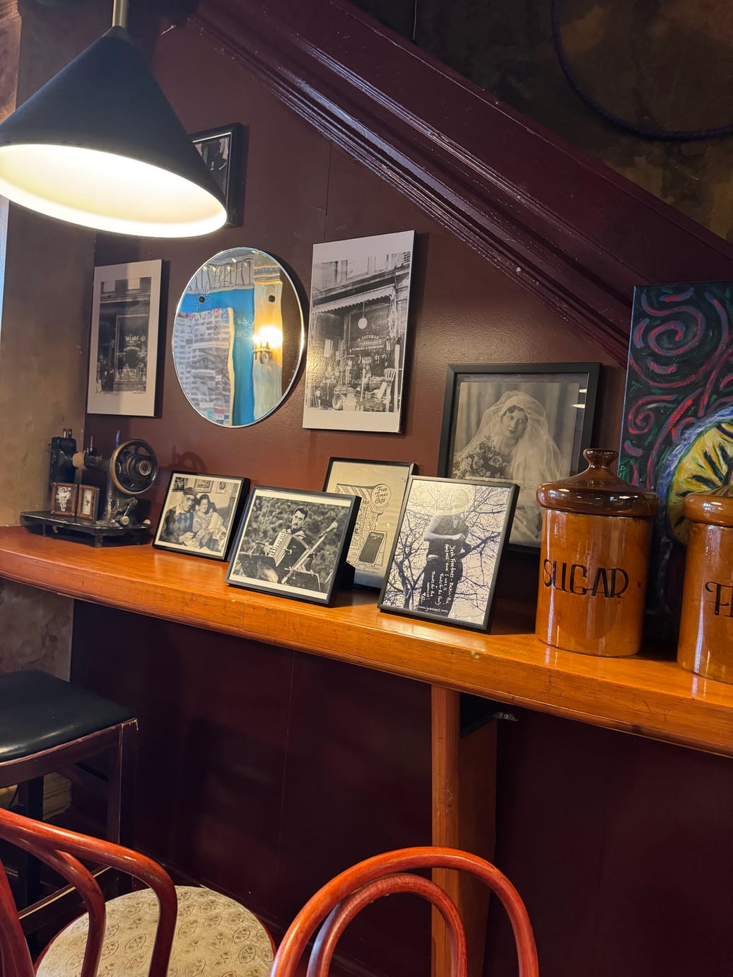 A shelf of framed black-and-white photographs and old jars under a pendant lamp inside Free Times Cafe